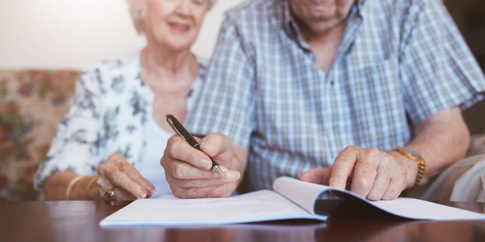 elderly-couple-signing-important-document elderly-couple-signing-important-document