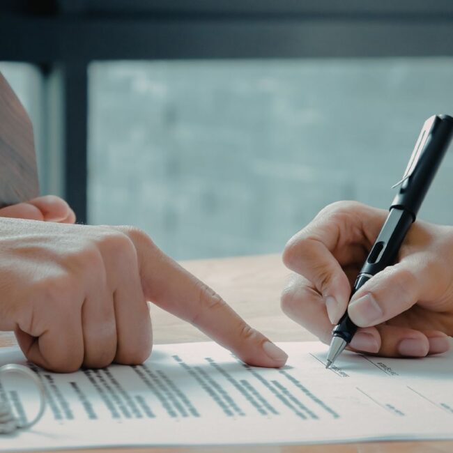 Why You Need to Write a Will Person signing a will with legal documents and family photos on desk.